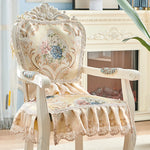 Fauteuil vintage en bois blanc avec un dossier sculpté et orné de fleurs bleues et roses, garni de dentelle, créant une atmosphère romantique dans cette pièce.