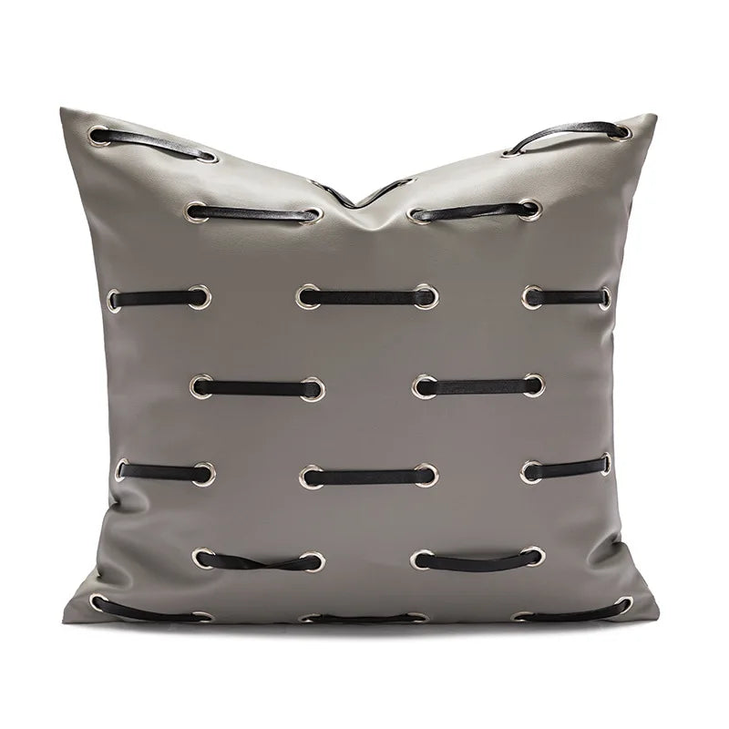 Coussin décoratif gris clair avec motifs brodés de cordons noirs.