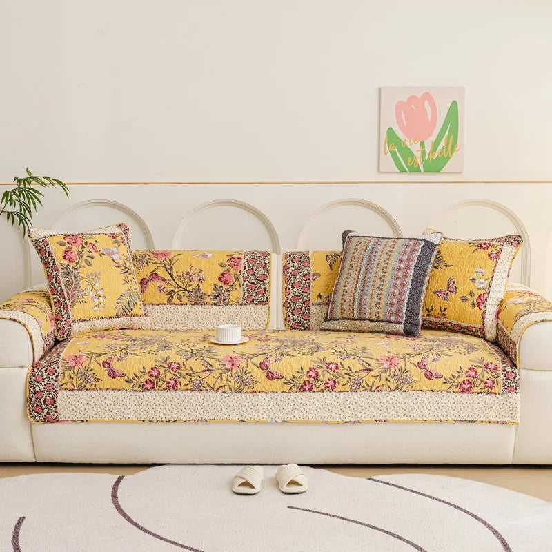 Un canapé confortable dans un style vintage avec des motifs floraux colorés et des coussins décoratifs, dans un salon lumineux et accueillant.