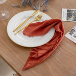 serviette table carrée orange franges moderne élégante fourchettes cuillères assiettesbranches séchées guirlande bougie parfumée