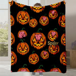 Une couverture noire avec de nombreuses citrouilles d'Halloween orange et roses sur le fond.