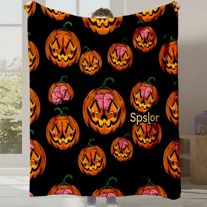 Une couverture noire avec de nombreuses citrouilles d'Halloween orange et roses sur le fond.