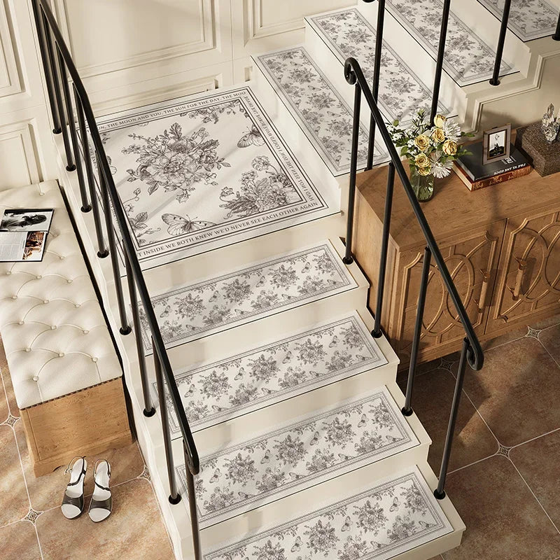 Élégant escalier aux motifs floraux gris et blancs, orné d'un bouquet de fleurs jaunes sur un meuble en bois, créant une atmosphère chaleureuse et raffinée.