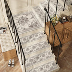 Élégant escalier aux motifs floraux gris et blancs, orné d'un bouquet de fleurs jaunes sur un meuble en bois, créant une atmosphère chaleureuse et raffinée.