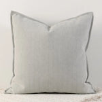 Coussin décoratif gris avec un motif de chevrons sur une surface blanche lisse.