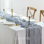 Une belle table de fête élégante avec des décorations en gris et or, y compris des chandelles, des verres de cristal et des couverts dorés, sur un fond blanc neutre.