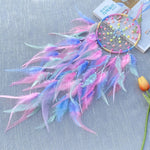 Un magnifique attrape-rêves coloré orné de plumes roses, bleues et vertes, suspendu à côté de fleurs dans un décor élégant.