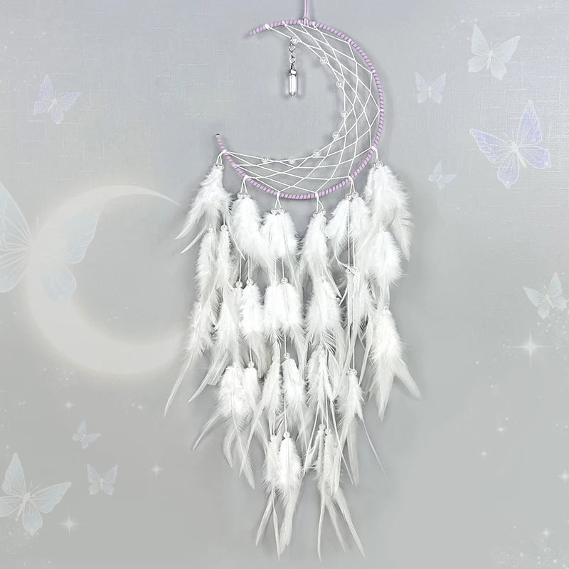 Cette image montre un capteur de rêves de lune blanche et argentée décoré de plumes blanches et violettes, suspendu sur un fond gris clair scintillant avec des papillons.