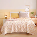 Une chambre design avec un lit moelleux, des coussins gris et une couverture motifs géométriques aux couleurs douces.
