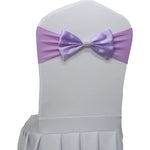 Nœud papillon lavande décorant le dossier d'une chaise blanche pour un événement élégant.