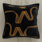 Coussin décoratif noir avec des motifs dorés abstraits.