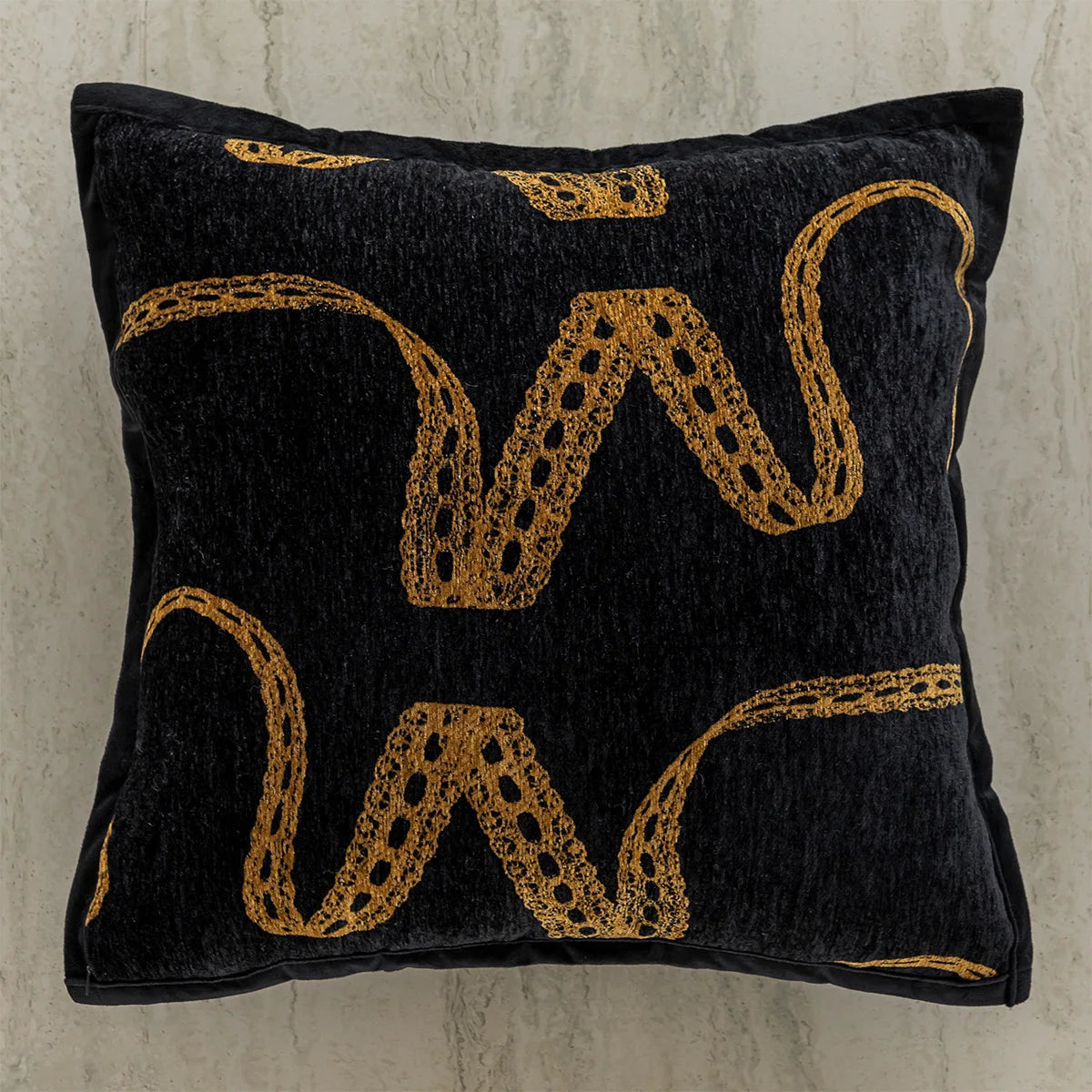 Coussin décoratif noir avec des motifs dorés abstraits.