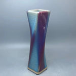 Un vase en céramique de forme conique aux couleurs dégradées bleu et violet, créant un effet visuel captivant.