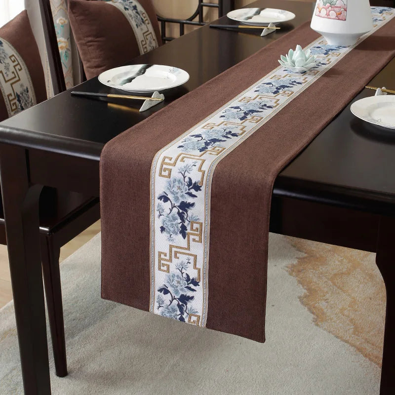 La table est décorée d'un chemin de table en tissu marron orné de motifs floraux et de motifs géométriques.