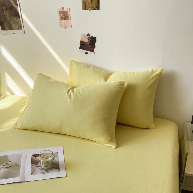 Ensemble de coussins et de draps de lit de couleur jaune pâle dans une pièce décorée avec des photos accrochées au mur.