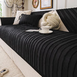 L'image montre un lit douillet avec un couvre-lit noir orné de coussins et d'un accessoire moelleux de forme noueuse, un décor élégant qui semble inviter à la détente.