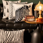 Ce salon élégant met en valeur des coussins décoratifs aux motifs de zèbres, ainsi qu'une lampe de table dorée et une radio vintage, créant une ambiance chaleureuse et sophistiquée.