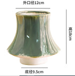 Vase en céramique vert olive de forme élégante avec une ouverture de 12 cm de diamètre et une hauteur de 18 cm.