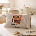 Un coussin décoratif rayé avec un vieux téléphone vintage orange, posé sur un lit dans une pièce lumineuse et élégante.