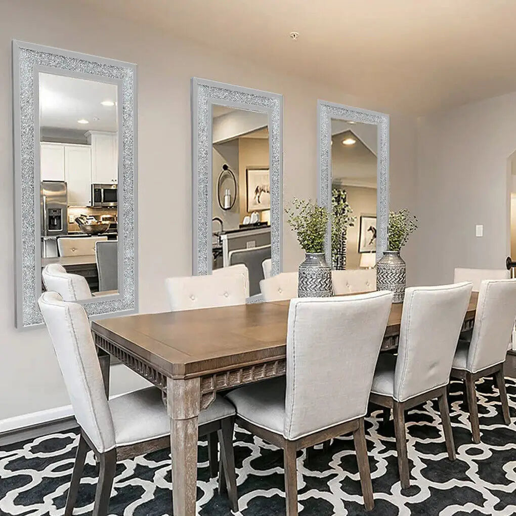 Cette image présente un intérieur élégant et moderne avec une table à manger en bois brut, des chaises rembourrées blanches et de grands miroirs ornés, le tout sur un tapis noir et blanc.