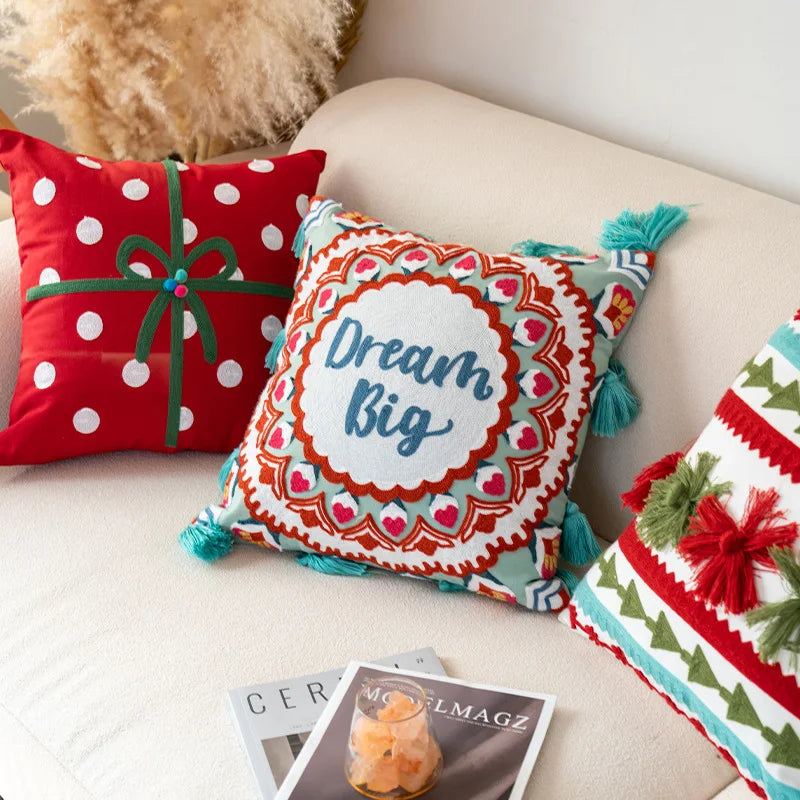 Coussin décoratif coloré avec l'inscription "Dream Big" et motifs géométriques et floraux.