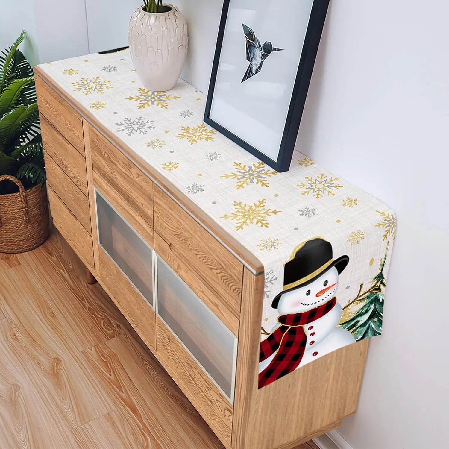 Un meuble en bois avec une décoration hivernale, comprenant un motif de flocons de neige et une image d'un bonhomme de neige en costume rouge et noir.