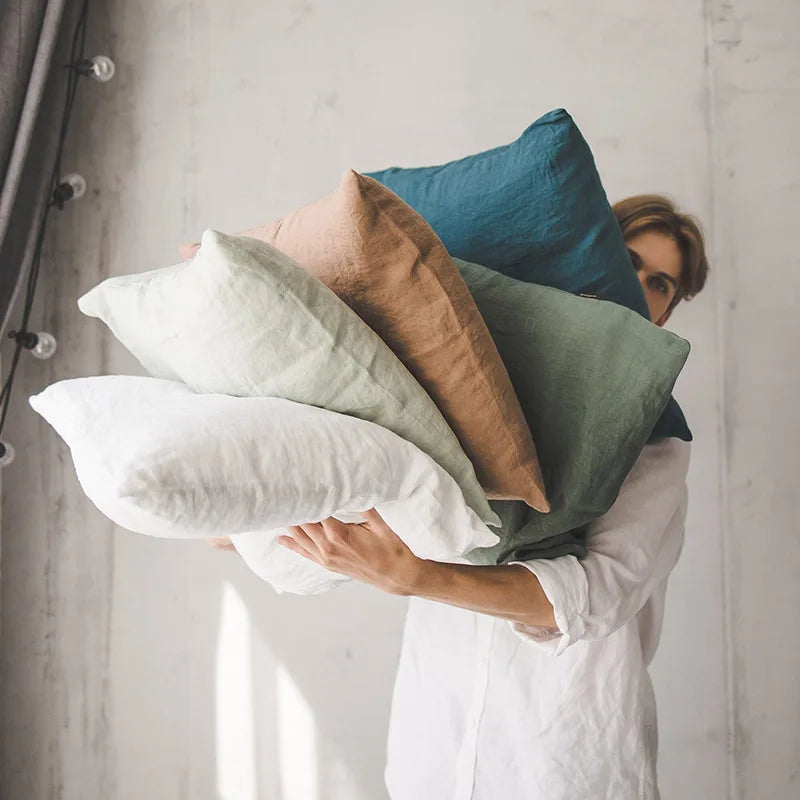 Une personne enveloppée de coussins moelleux dans diverses nuances de vert et de beige, créant une atmosphère confortable et apaisante.