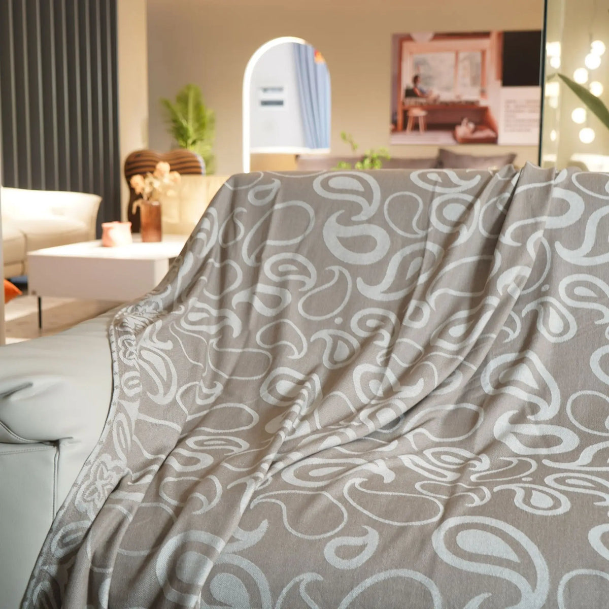 Couverture grise motif abstrait, créant une ambiance douce et paisible dans la pièce.