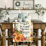 Cette image présente une belle table de salle à manger décorée pour l'automne, avec des citrouilles, des bougies et une pancarte en bois avec un texte religieux.