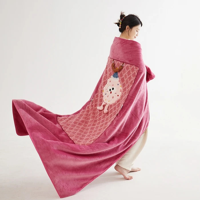 Une femme enveloppée dans un châle rose vif, décoré d'un motif de visage souriant, se tient debout dans une pose gracieuse.