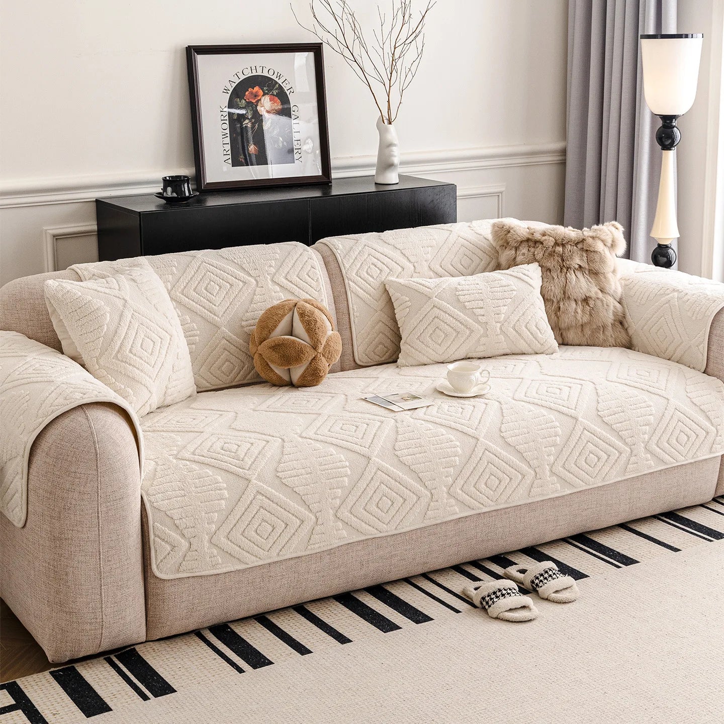 Un canapé moelleux avec des motifs géométriques, accompagné d'un cadre décoratif et d'un vase de fleurs, créant une ambiance chaleureuse et invitante dans cette pièce de style moderne.