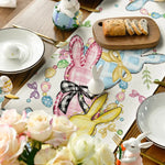 Table décorée avec des fleurs, des objets de Pâques, des assiettes et des couverts, créant une ambiance festive et printanière.