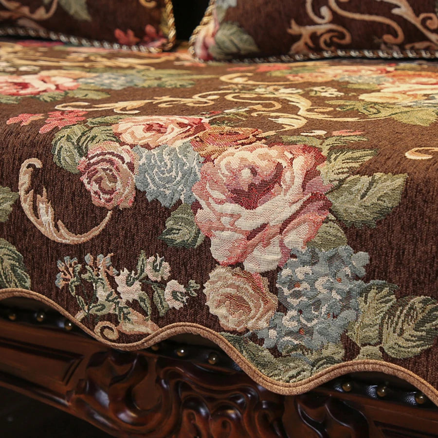 Cette image montre un motif floral décoratif sur un tissu aux couleurs chaudes et profondes, avec des roses et des feuilles dans des tons de rouge, de vert et de brun.
