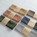 serviettes tissu pliées rustique bohème minimaliste liens anneaux couleurs beige rose vert bleu gris