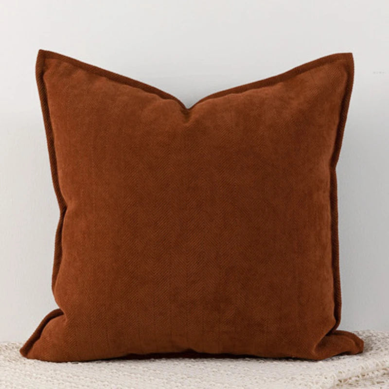 Coussin carré marron en tissu velours, posé sur un sol clair, représentant un accessoire de décoration élégant et confortable.