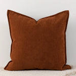 Coussin carré marron en tissu velours, posé sur un sol clair, représentant un accessoire de décoration élégant et confortable.
