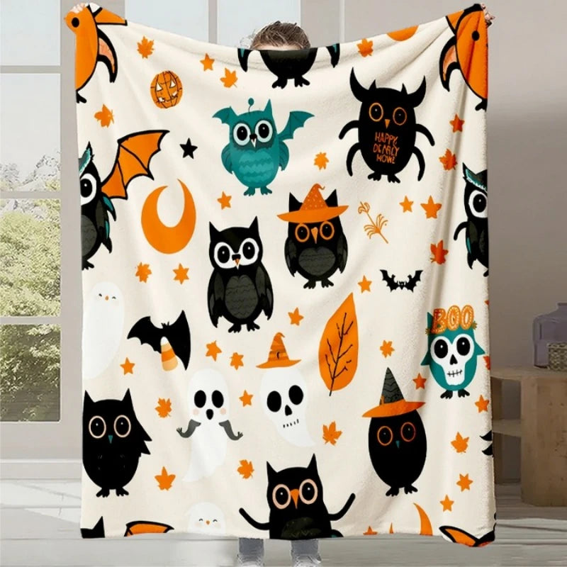 Une couverture blanche ornée de chauves-souris, de hiboux et de feuilles d'automne colorées, créant un décor festif et amusant pour la période d'Halloween.