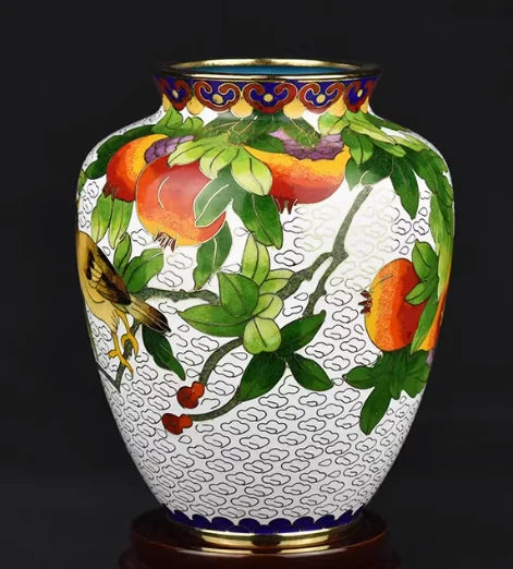 Un vase élégant décoré de feuilles vertes et de fruits colorés sur un fond sombre.