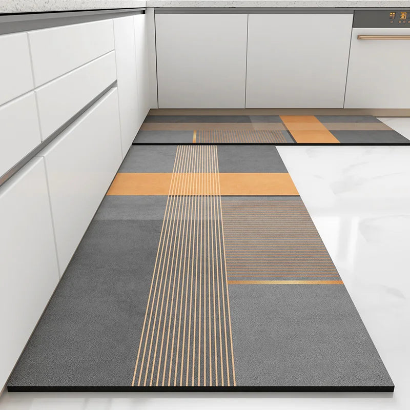 Revêtement de sol moderne et géométrique dans une cuisine grise et blanche, composé de motifs rectangulaires et de lignes diagonales dans des nuances de gris et d'orange.