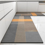 Revêtement de sol moderne et géométrique dans une cuisine grise et blanche, composé de motifs rectangulaires et de lignes diagonales dans des nuances de gris et d'orange.