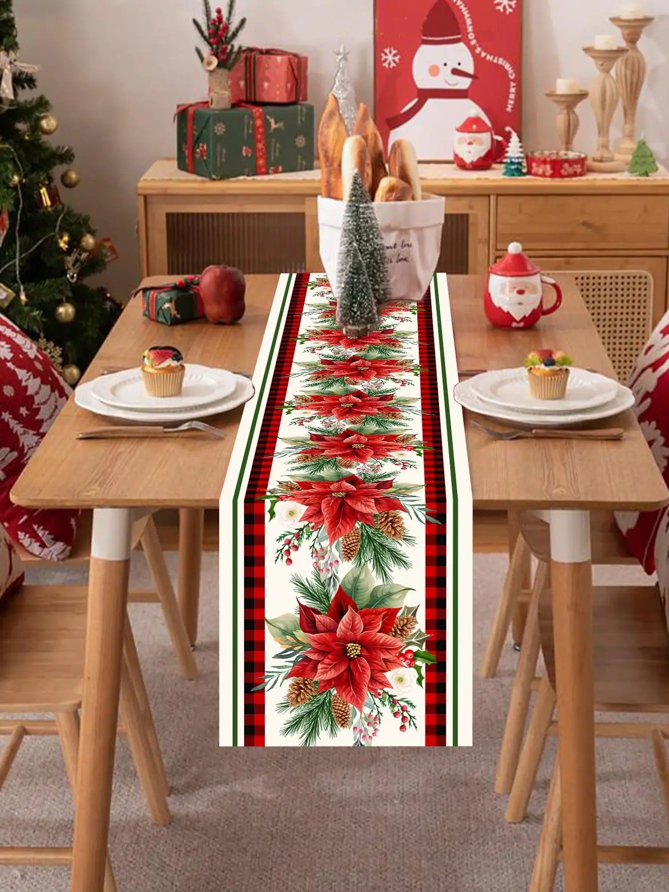 La table de la salle à manger est joliment décorée avec des décorations de Noël, notamment un chemin de table avec des motifs de fleurs de poinsettia et de sapins.