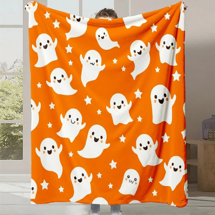 Une couverture orange vif avec des fantômes aux expressions avenantes et des étoiles blanches dispersées, créant une atmosphère chaleureuse et festive pour la période d'Halloween.