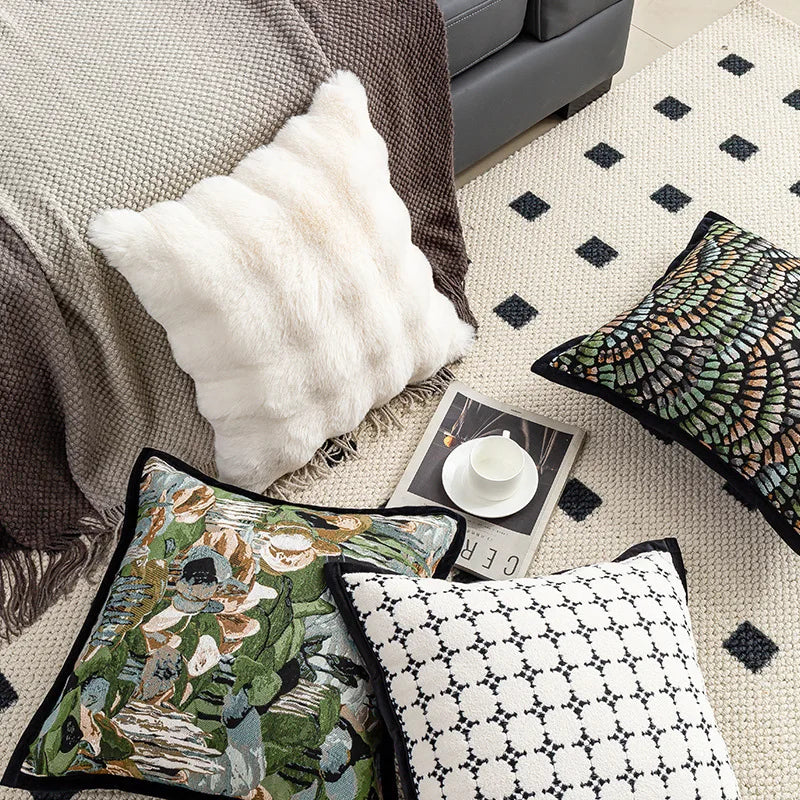 Cette image démontre une décoration de chambre élégante et moderne, avec des coussins aux motifs géométriques et floraux, ainsi qu'une couverture et un tapis texturés.