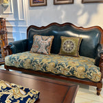 Un canapé vintage en cuir vert foncé avec des coussins et un motif floral doré, créant une atmosphère élégante et luxueuse dans cette pièce d'intérieur.