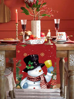 Une table de fête de Noël décorée avec des bouquets de fleurs, des bougies, et une jolie nappe avec un motif de bonhomme de neige en gros plan.
