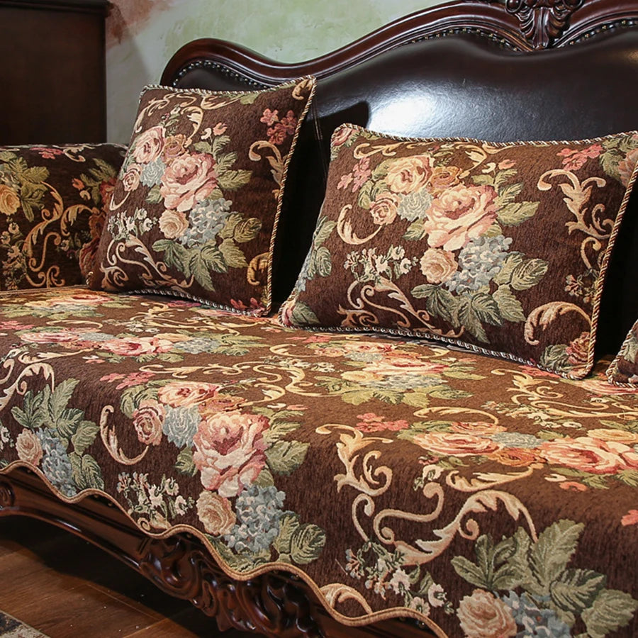 Canapé vintage élégant avec un motif floral luxuriant sur les coussins et un cadre sculptural en bois foncé.