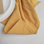 Cette image montre des plis et des froissements dans un tissu léger et doux, avec des tons chauds et un éclairage naturel qui crée des ombres et des textures intéressantes.