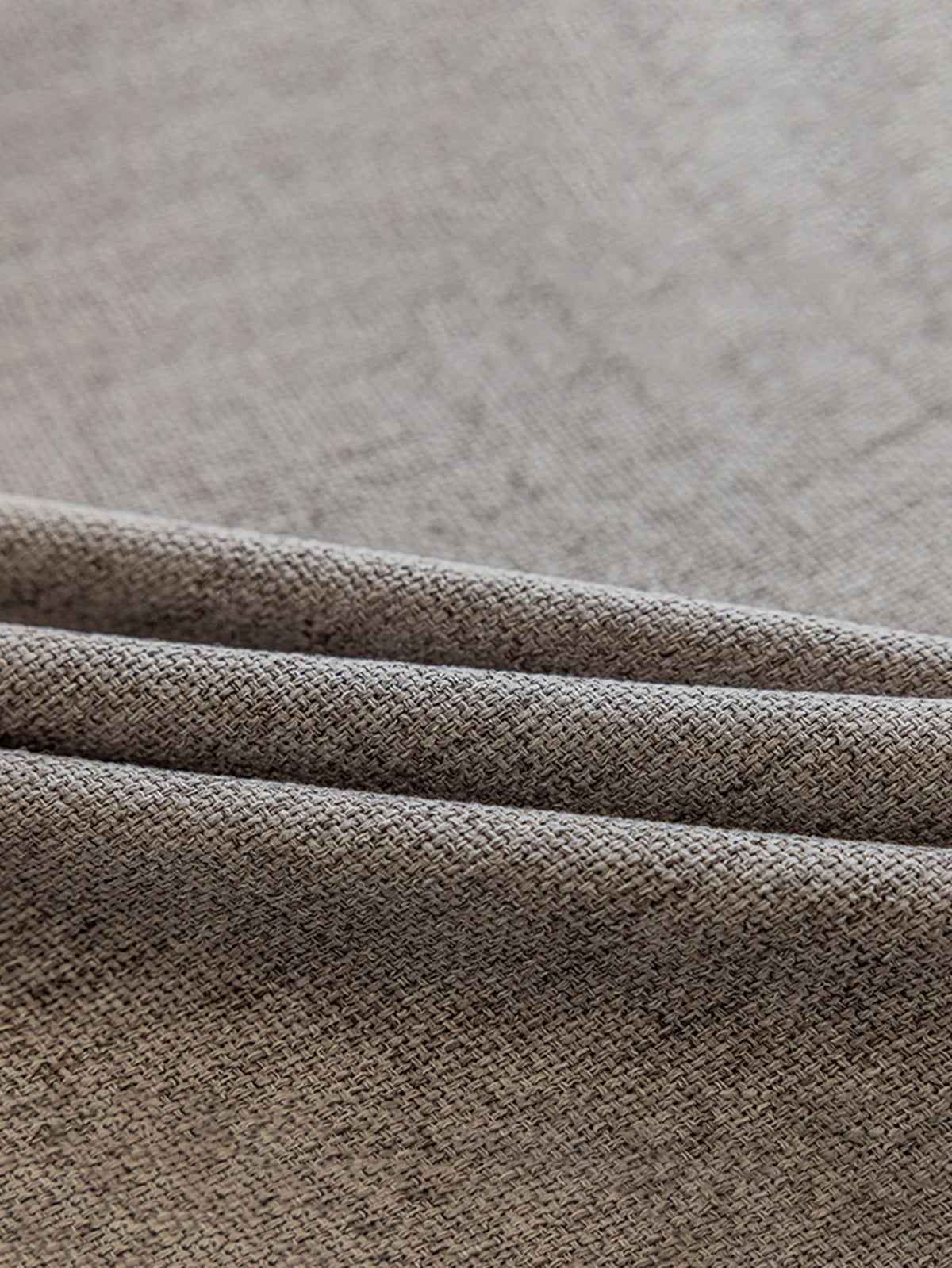 Détail du tissu texturé du voilage occultant gris clair posé à plat.