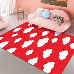 Un tapis rouge décoré de nuages blancs moelleux, posé dans un salon moderne et coloré avec un canapé rose et des accessoires décoratifs.