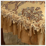 Motif floral décoratif en dentelle dorée sur un tissu de couleur ocre, avec des éléments floraux et des franges pendant à la bordure.